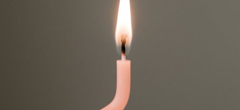 burning pink candle against gray background
