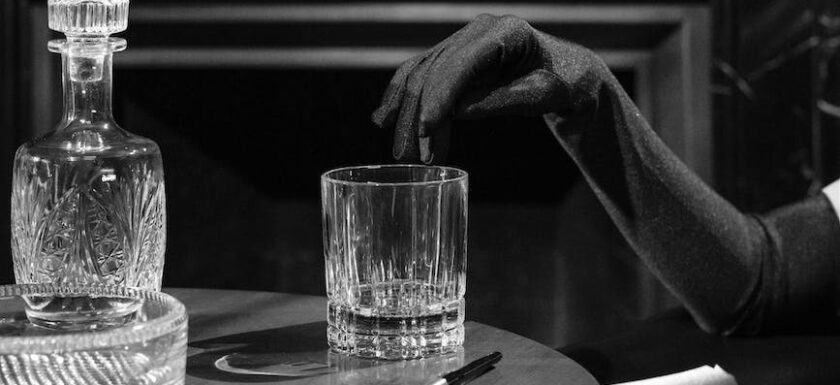 monochrome photo of woman s fingers on the edge of drinking glass